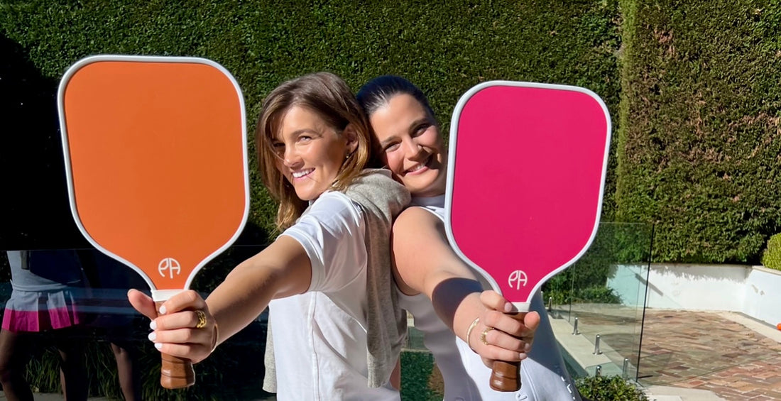 Two girls with pink and orange pickleball paddles
