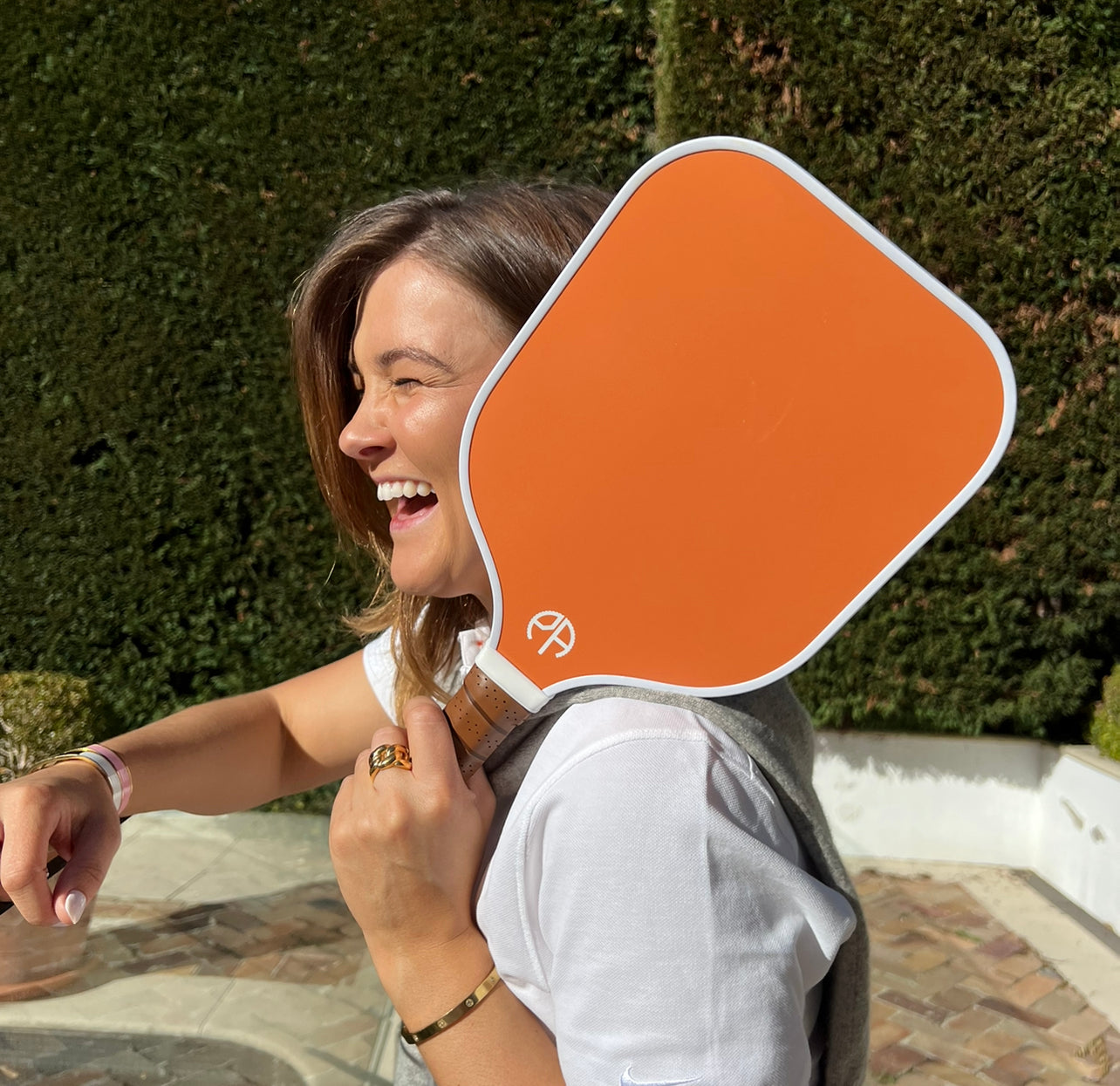 Girl laughing while holding a pickleball paddle.